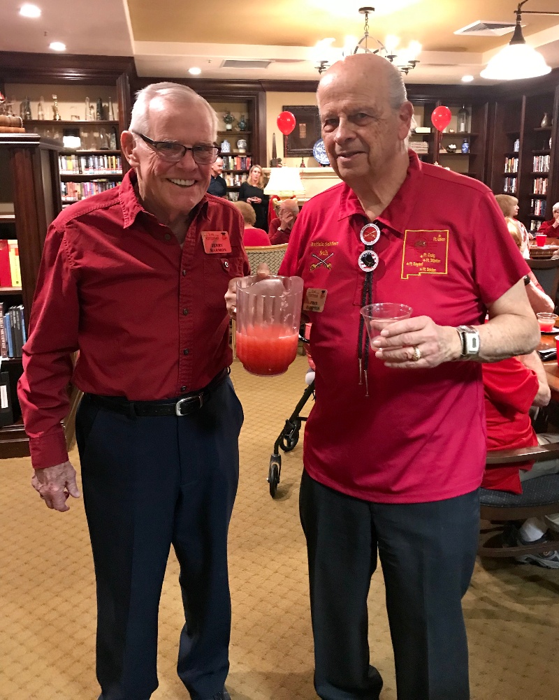 Two men wearing red and holding a pitcher of a red drink