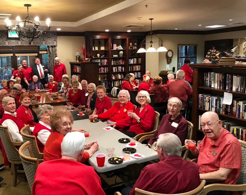 A group of seniors wearing red and sitting around a table.