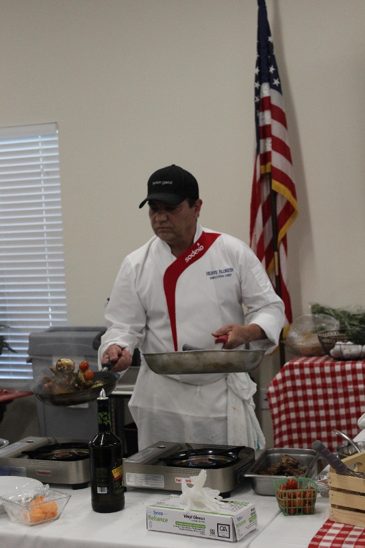 Chef holding two frying pans and tossing food in the air.