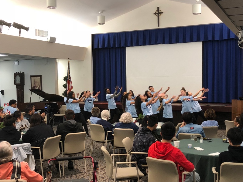 A group dancing with their arms in the air in an auditorium.