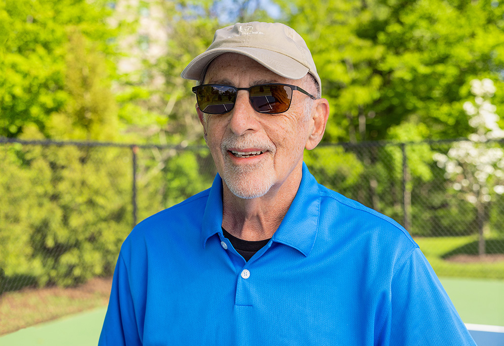 Joel smiling outside on a pickleball court