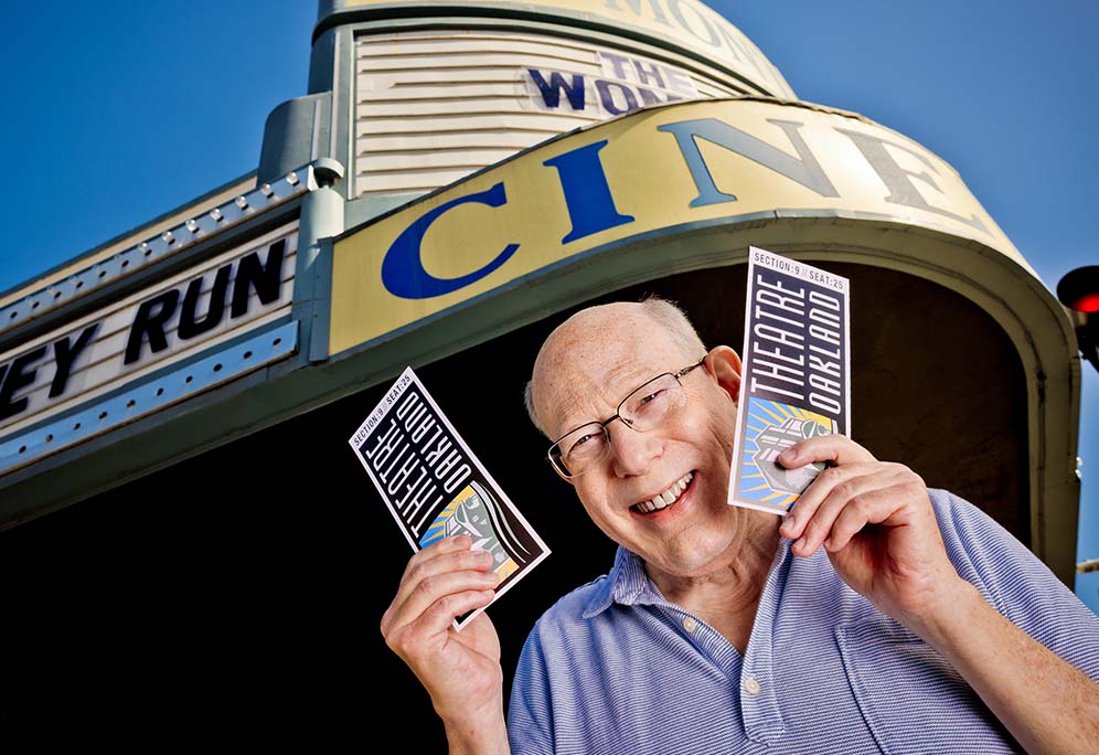 Allen smiling outside theater while holding two tickets