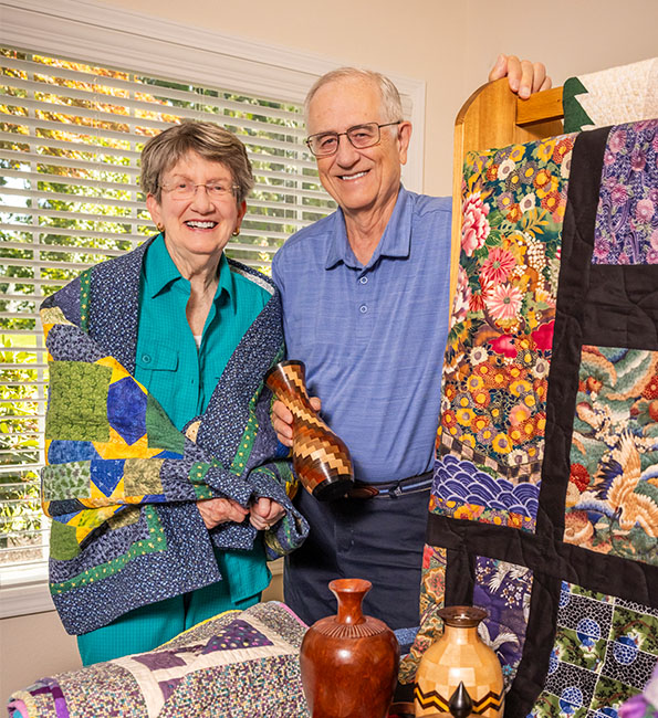 Eileen and Jim holding a quilt and wood vase