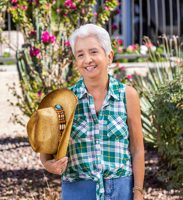 Marti outside holding a straw hat
