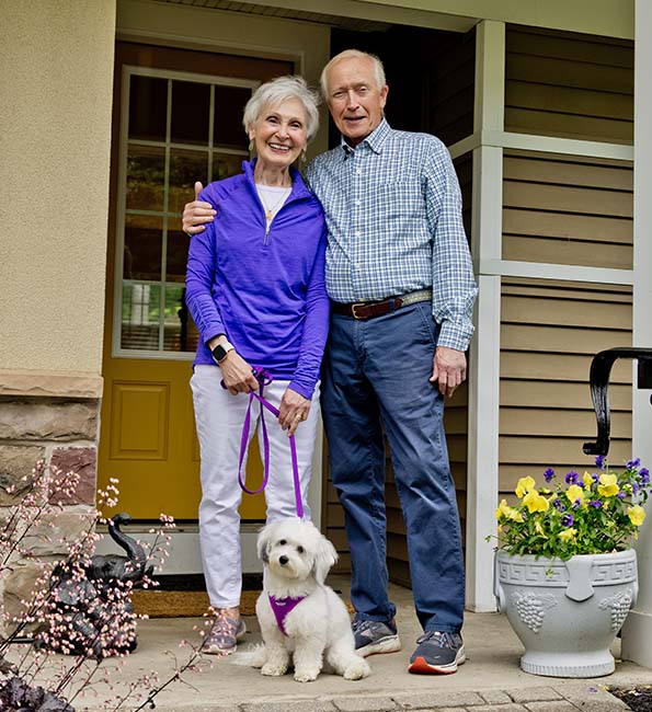 Mike and Linda on the porch of their home with their small dog