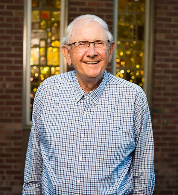 Paul smiling and standing near a lit window