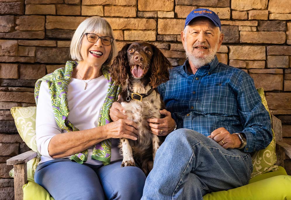 Tom and Mary sitting on an outdoor bench with their dog