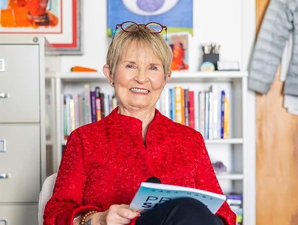 Senior woman sitting in office with a magazine in her hands