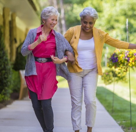 two women walking arm in arm outside