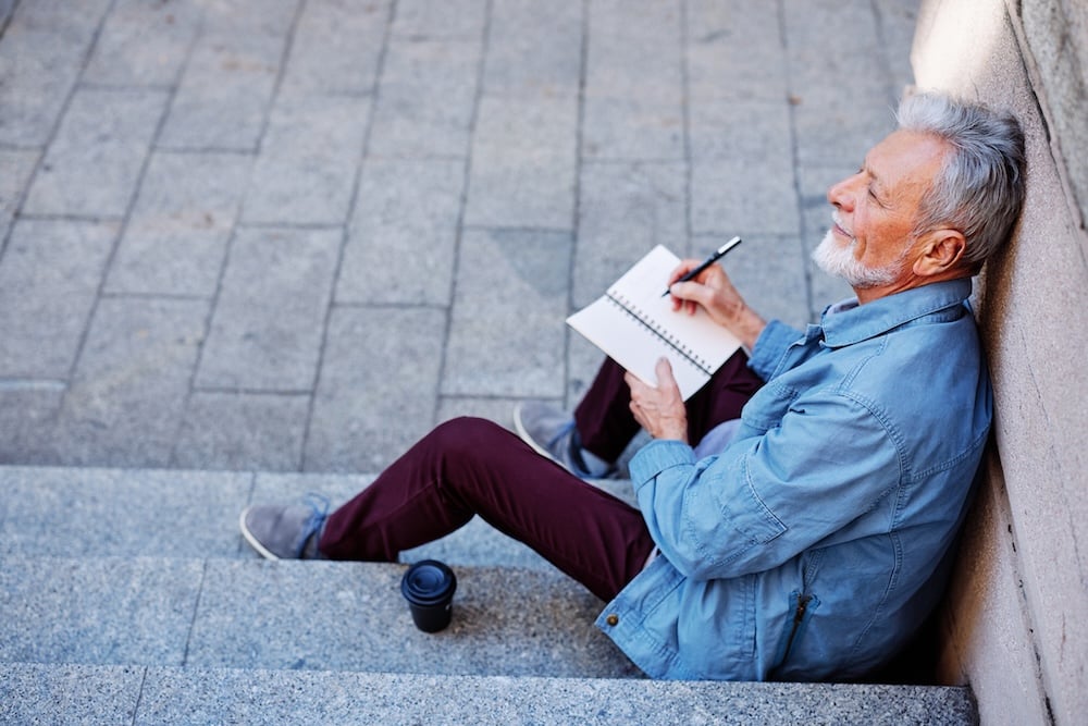 man sitting outside and writing to do list