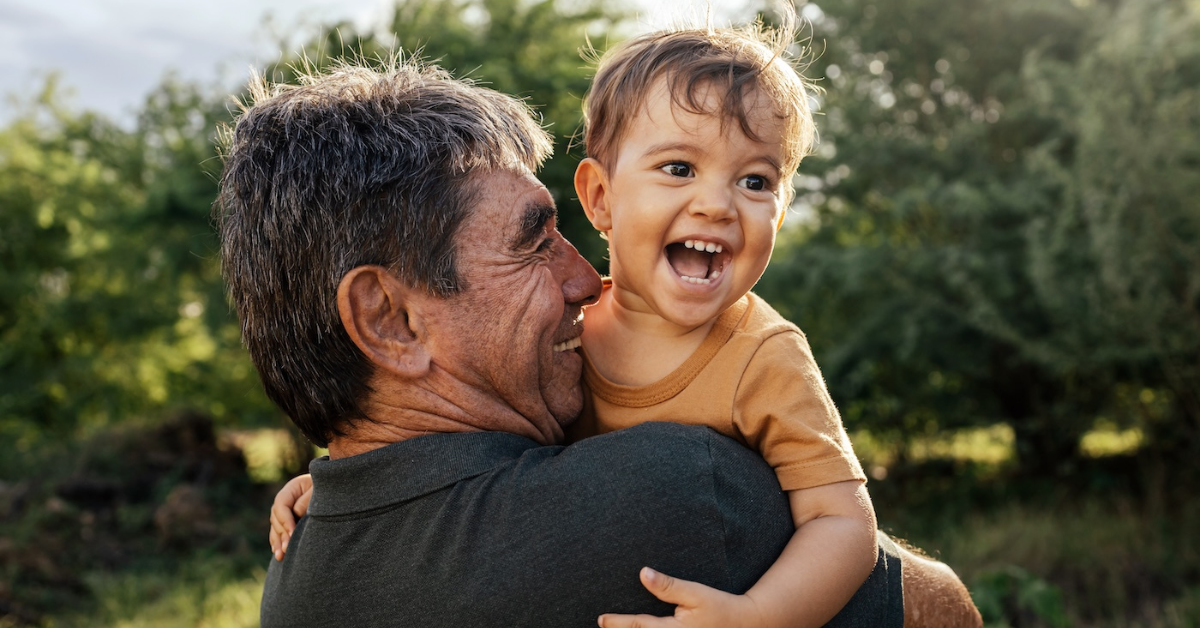 grandfather holding young grandson and laughing