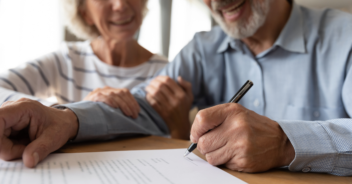senior man and woman smiling as they write their will