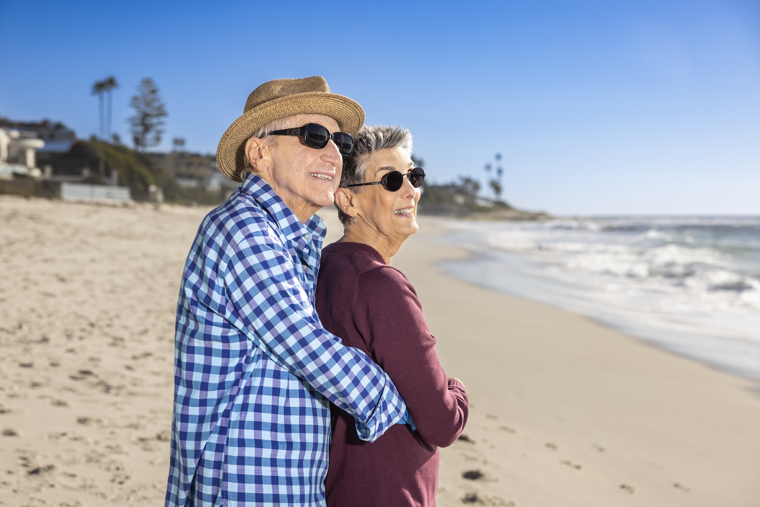 Marilyn and Bob embracing on the beach while looking out at the water