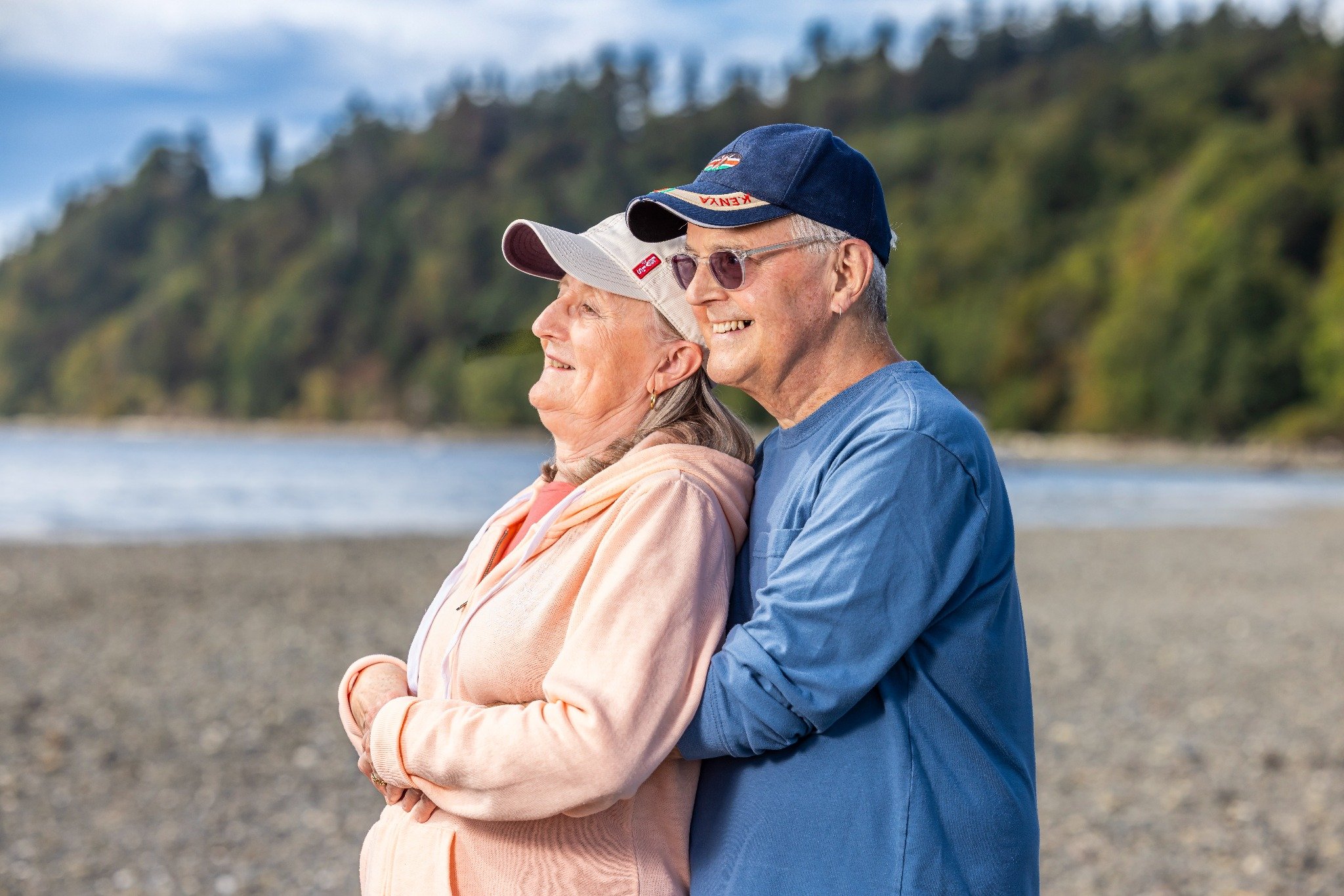 Rick and Susan smiling together on a rocky beach.