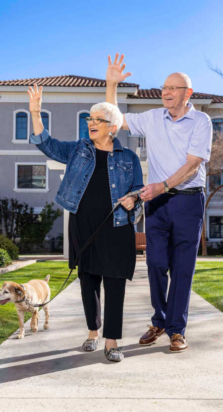Couple walking their dog and waving