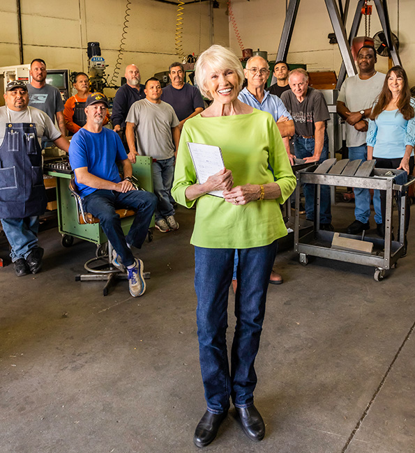 Carolyn smiling and standing in front of a group of people in a workshop