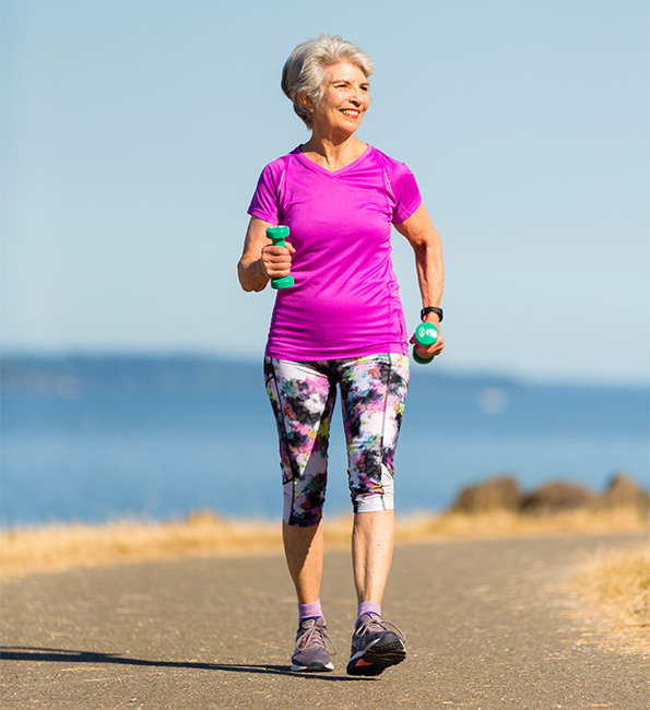 Janet walking an an outdoor path while holding dumbells