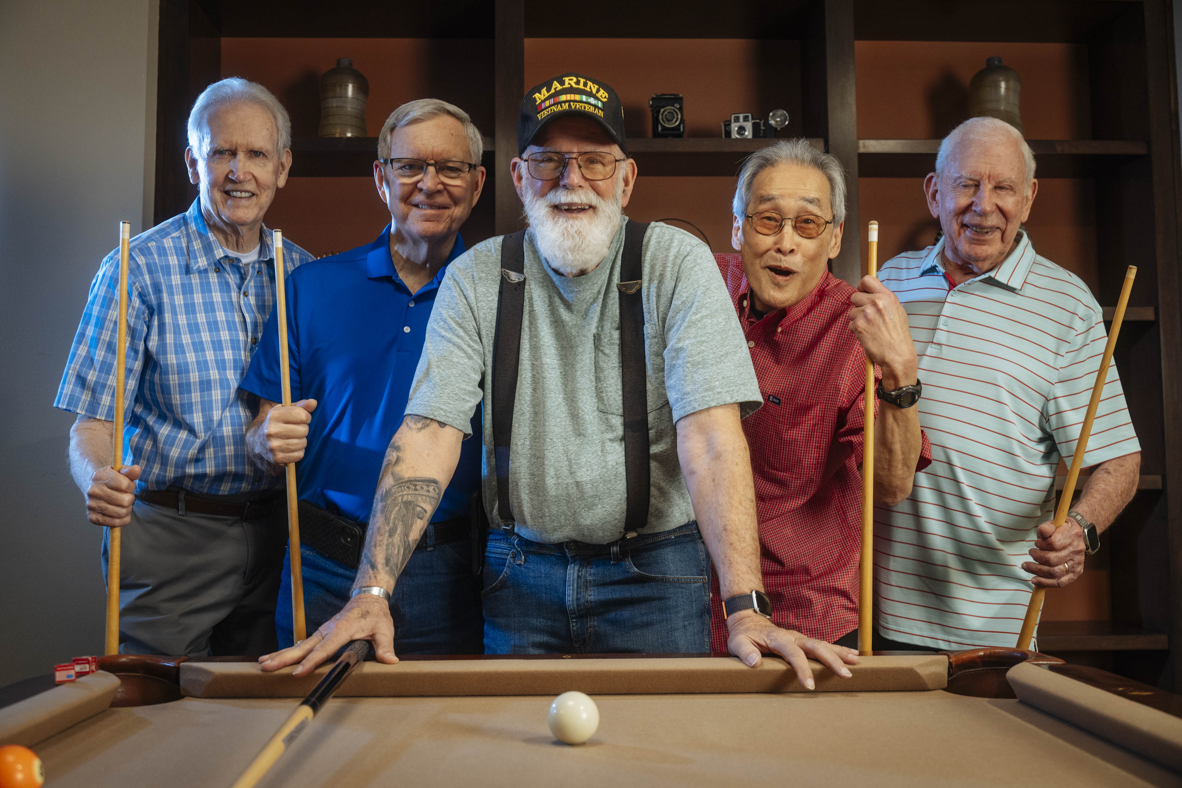 Dan and the other men are standing ready to play pool.