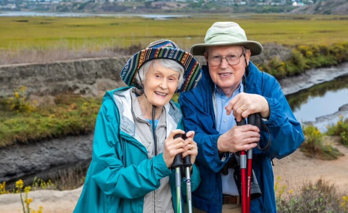 Senior couple wearing hats outside holding hiking poles