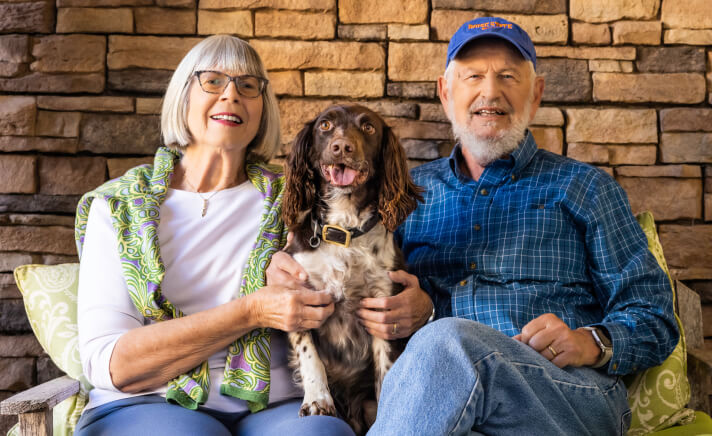 Senior couple sitting with their dog in between them
