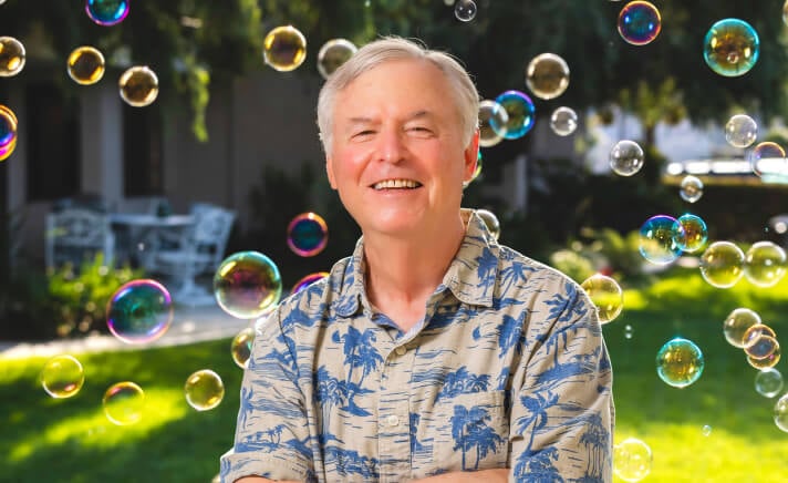 Senior man standing outdoors surrounded by bubbles