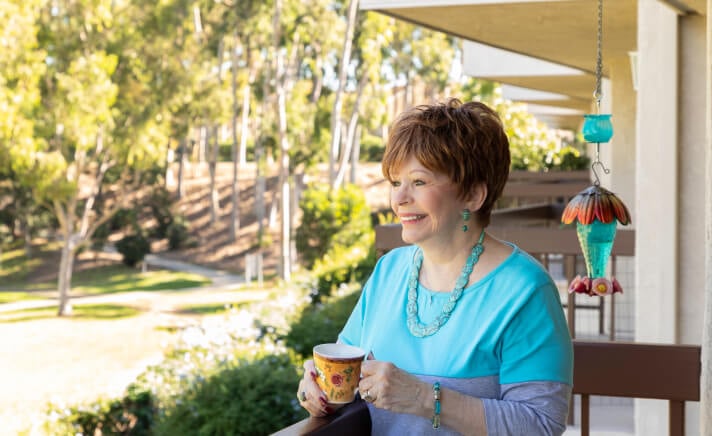 Senior woman drinking a cup of coffee on a balcony