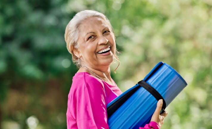 Senior woman holding a rolled-up yoga mat