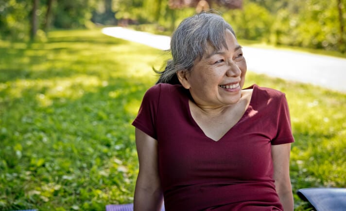 Senior woman sitting outside in the grass