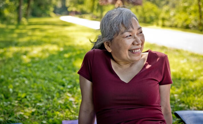 Senior woman sitting outside in the grass