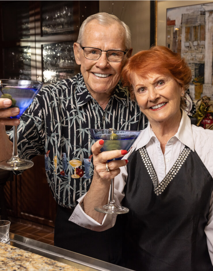 Jerry and Kay holding up martinis inside a bar setting