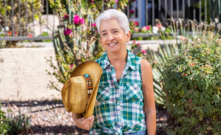 Senior woman outdoors holding a hat