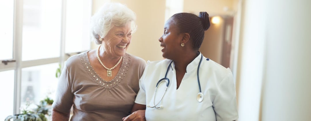 Nurse helping a woman walk down the hall