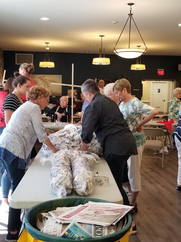 Royal Oaks Residents making a scarecrow body out of newspaper.