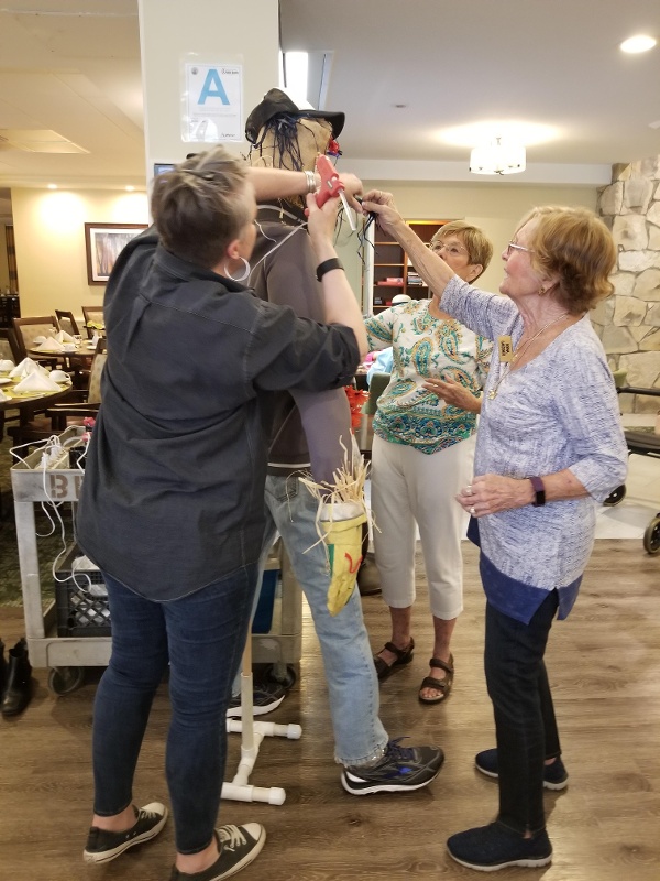 Royal Oaks Residents gluing details onto their scarecrow.