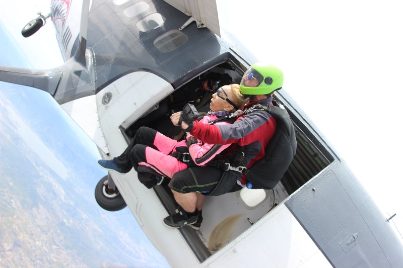 A woman and instructor jumping out of a plane